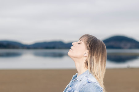 Captivating Beauty: Dreamy Woman Finds Serenity by the Coastal Horizon with Closed Eyesの写真素材