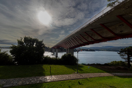 A Serene Walkway Over Water: Red and White Bridge in a Green Parkの写真素材