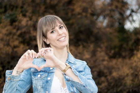 Heartfelt Gesture: woman Making Heart Shape in Natureの写真素材