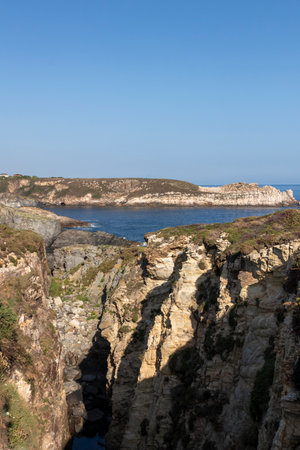 Rugged Beauty of a Cliffside Coastline Under a Clear Blue Skyの写真素材