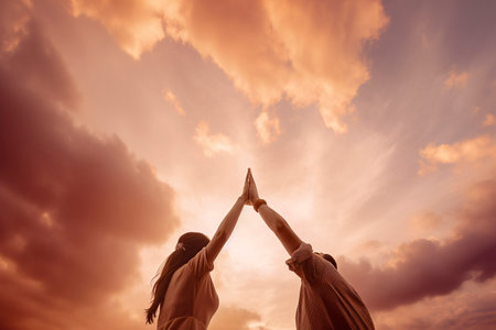 The Joy of Togetherness: Friends Sharing a Beautiful Sunset on a Grassy Fieldの素材