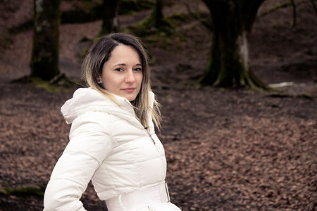 woman in a white coat standing in a forestの写真素材
