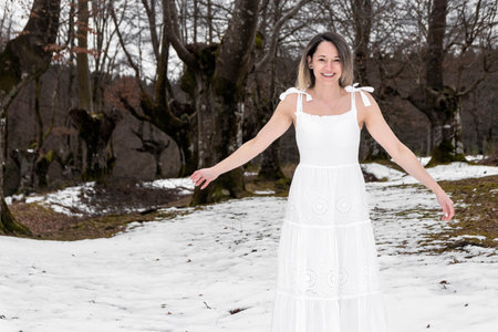 woman in a white dress standing in a snowy forestの写真素材