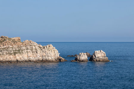 white rocky coastline with the deep blue ocean in the background under a light blue skyの写真素材
