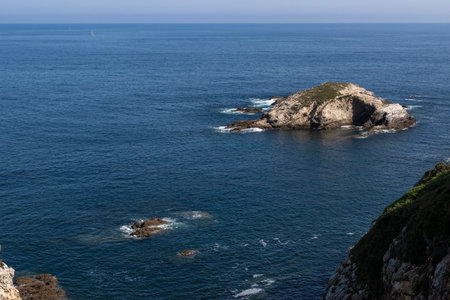island in the ocean, with calm, deep blue waters and a clear blue skyの写真素材