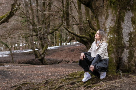 woman sitting on a tree in a forest in autumnの写真素材