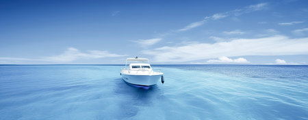 white boat on a bright blue ocean, taken from a low angle, with a clear blue sky and horizon in the backgroundの素材