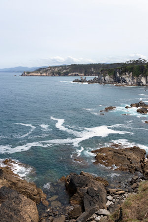 rocky coastline with the ocean and cliffs in the background, taken from a high vantage point on a sunny dayの写真素材