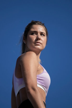 woman in sportswear against a bright blue sky, their face obscured for privacy