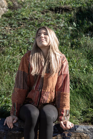 pretty blonde woman sitting on a stone wall happyの写真素材