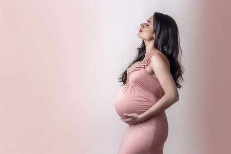 a pregnant woman in a pink dress, standing against a light pink backgroundの素材