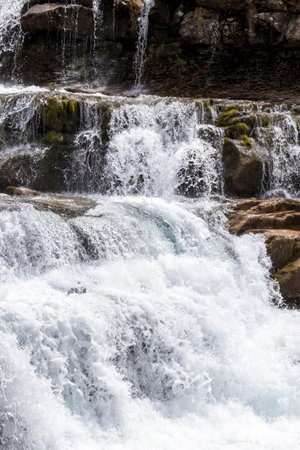 lively waterfall cascading over rocks, surrounded by moss, embodying the energy and beauty of natureの写真素材