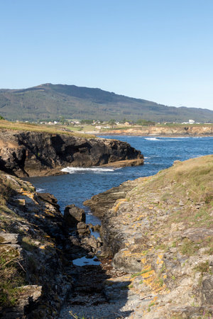 view of rocky shores, blue waters, distant mountain, clear sky, and bright day with serene natural landscape.の写真素材