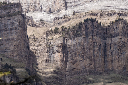 cliffs with distinct layers and erosion patterns, surrounded by sparse vegetation under a clear sky, showcase nature's artworkの写真素材