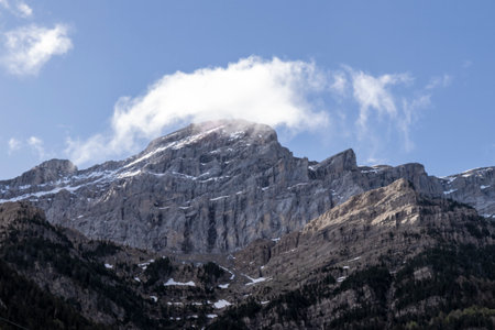 a majestic mountain peak with snow under a blue sky, accented by white cloudsの写真素材
