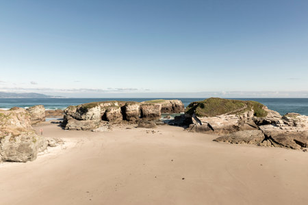 formations and sandy beach with ocean in the background under clear blue sky. Coastal landscape photography. Summer vacation and travel conceptの写真素材