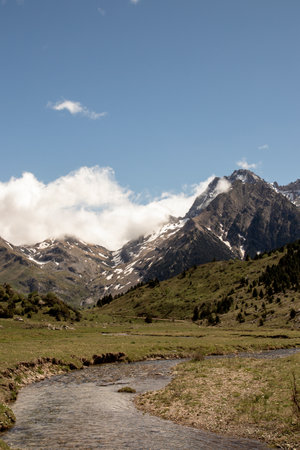 Mountain Valley with Snow-Capped Peaks and Flowing Streamの写真素材