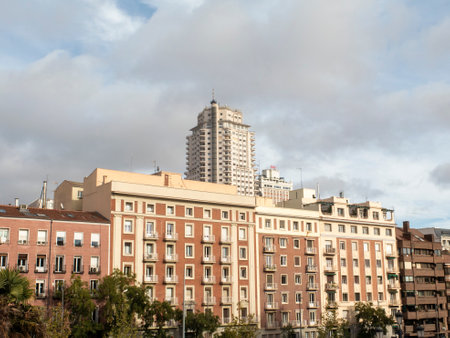 Urban skyline with classic apartment buildings and a tall skyscraper in the background under cloudy...