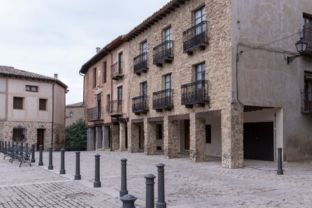 Charming historic village square with stone buildings, wrought iron balconies, and a cobblestone plazaの写真素材