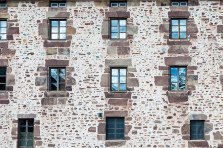 Stone facade with symmetrical windows reflecting the blue sky, creating a captivating architectural...