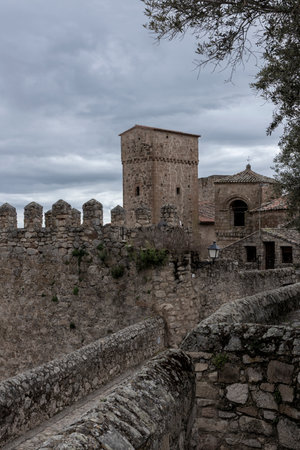 Stone walls and tower of a medieval castle rising under a cloudy sky, creating a dramatic and historic sceneの写真素材