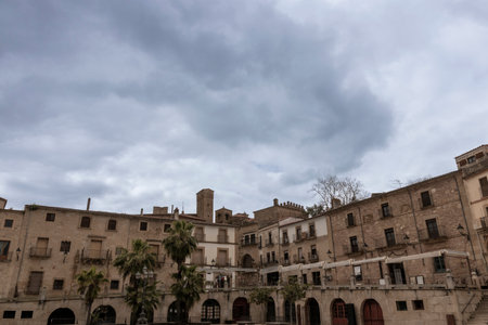 PlaÃ§a major, main square of besalÃº, showcasing its unique medieval architecture under a dramatic cloudy skyの写真素材