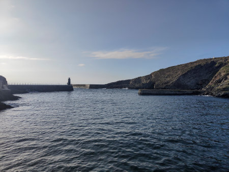 Scenic view of a lighthouse on a pier leading into the harbor on a sunny dayの写真素材