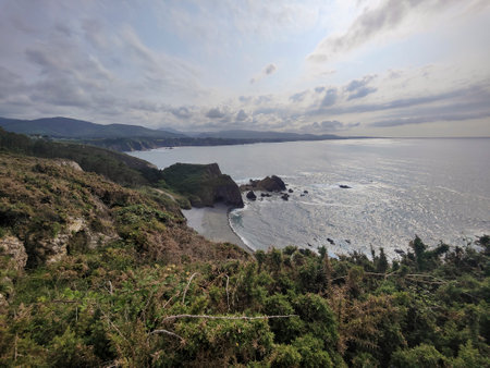 Stunning scenery unfolds along the rugged coastline, where cliffs meet the vast ocean under a cloudy...