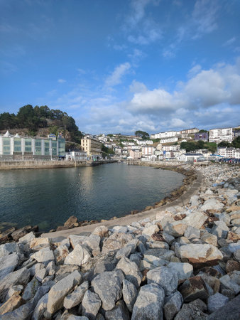 Tranquil bay reflects the charm of a coastal town, nestled amidst rolling hills, under a serene skyの写真素材