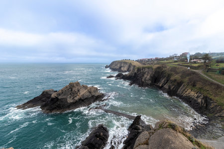 Scenic view of the rocky coastline of northern spain with waves crashing against the rocks on a cloudy dayの写真素材