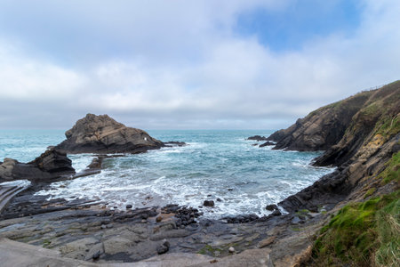 Ocean waves crashing against a rocky coastline on a cloudy day