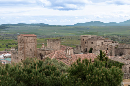 Trujillo medieval castle rising above the tiled roofs and overlooking the vast plains of extremadura, spain, under a cloudy skyの写真素材