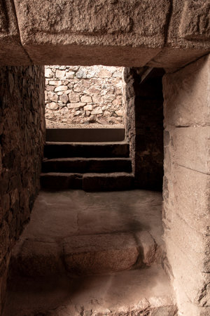 Exploring the mysterious passage within the ruins, ascending stone steps towards a distant light sourceの写真素材
