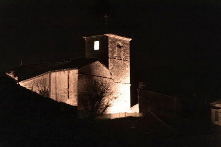 Stone church tower glowing against the dark night skyの写真素材