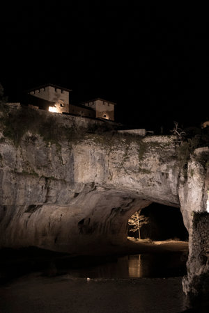 Nighttime view of a lit castle above a natural caveの写真素材