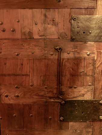 Antique wooden door with metal elements, illuminated by warm light, showcasing age and historyの写真素材
