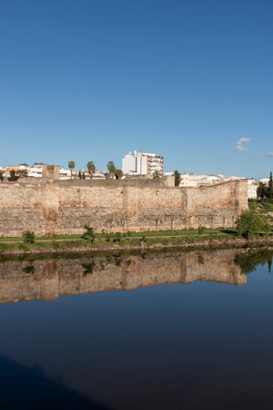 The serene albarregas river mirrors the historic city walls of merida, spain, creating a picturesque scene under the clear blue skyの写真素材