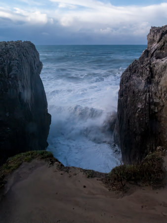Ocean waves crashing between cliffs on a cloudy day on the coast of asturias, spainの写真素材