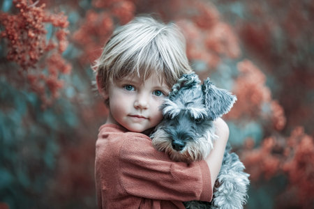 Little boy embracing a friendly schnauzer dog in an outdoor autumn settingの素材