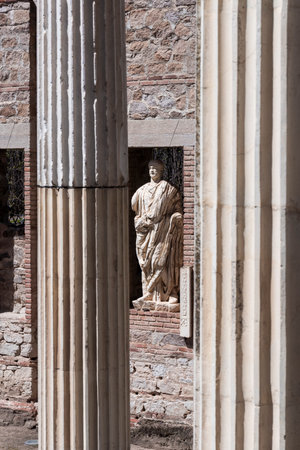 White marble statue standing among ancient roman columns and brick ruins in MÃ©rida, Spain