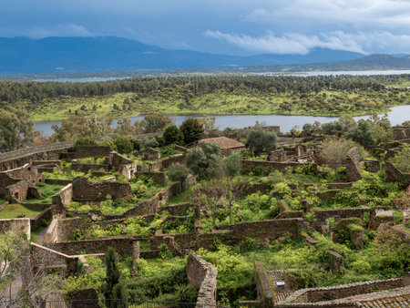 Granadilla abandoned village structures with nature reclaiming the stone walls and buildings near a reservoirの写真素材