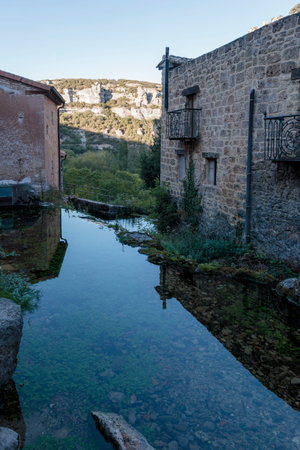Stone buildings of orbaneja del castillo village reflecting in the ebro river