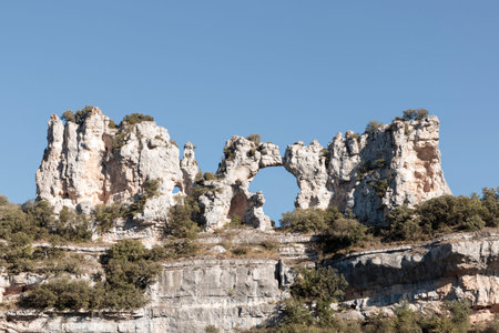 Natural rock formation showing a stone arch in a cliff with blue sky