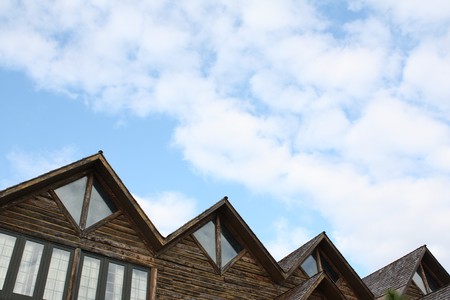 Rustic roof peaks against soft cloudsの写真素材