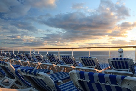 Cruise deck beach chairs with ocean sunset backgroundの写真素材