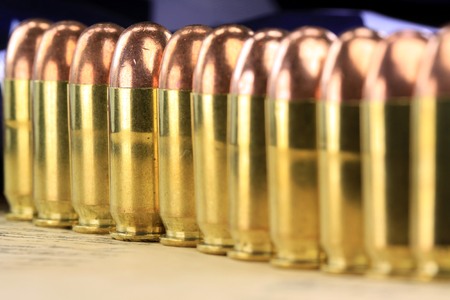 A stack of copper plated bullets with brass slugs lined in rows