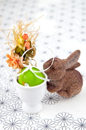 Painted green Easter Egg in a egg-cup with toy-rabbit