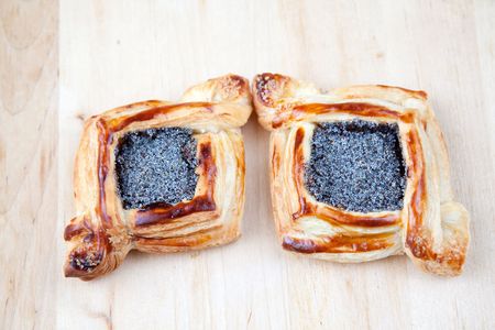 Freshly baked flaky croissant with poppy on a wooden desk の写真素材