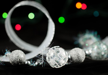 Silver christmas balls and colorful lights on the black backgroundの写真素材