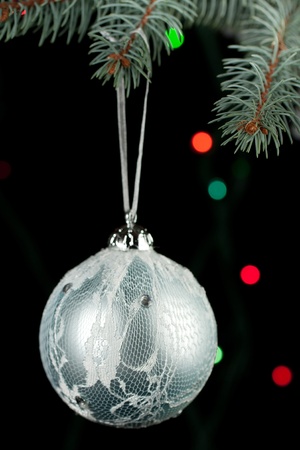 Silver christmas ball on a christmas tree on the black background and colorful lightの写真素材